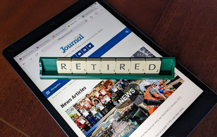 Photo of letter tiles spelling the word 'Retired' in a rack placed over a webpage displayed on an iPad.